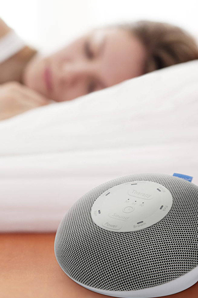 Woman sleeps next to a Homedics Deep Sleep Mini sound machine