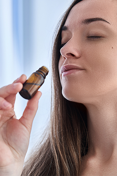 Woman holds bottle of essential oils to her nose, closes her eyes and relaxes