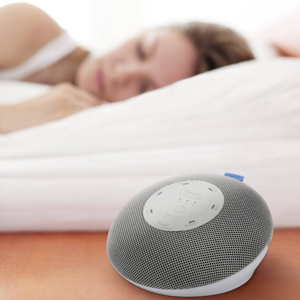 Woman sleeps next to a Homedics Deep Sleep Mini sound machine.