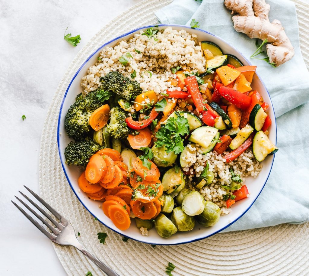 Top-down view of a bowl of healthy fresh, healthy vegetables on a place mat next to a fork and napkin