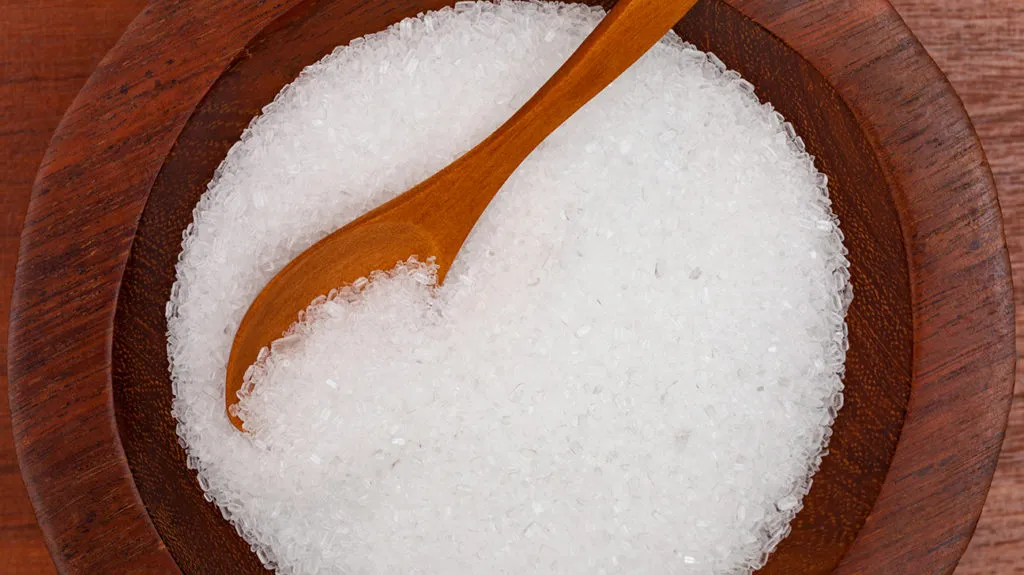 Top-down view of epsom salt in wooden bowl with a wooden spoon