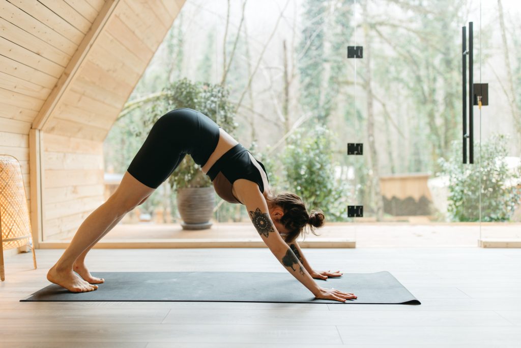 Woman on yoga mat positions in downward facing dog to stretch tight hamstrings