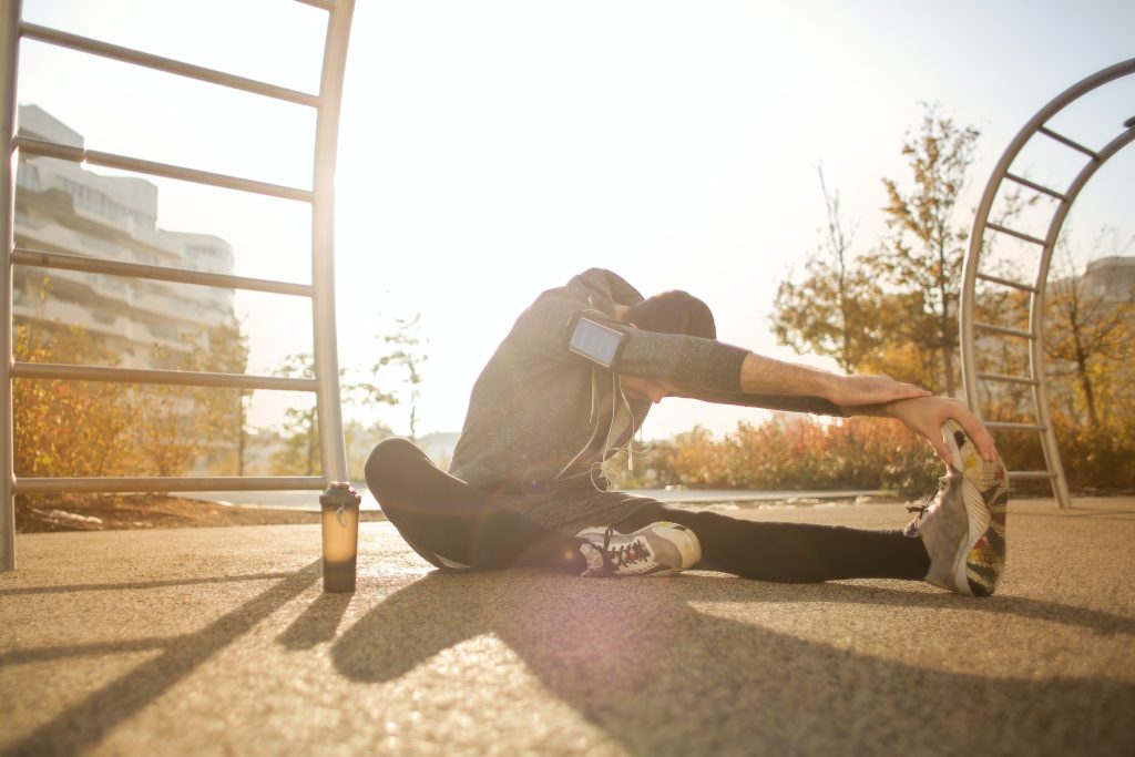 Man does a seated hamstring stretch while preparing for a run