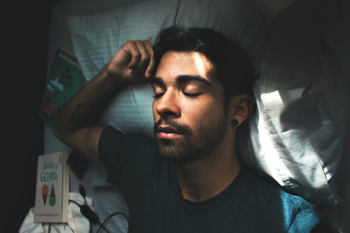 Close up of man asleep in bed with arm stretched across pillow