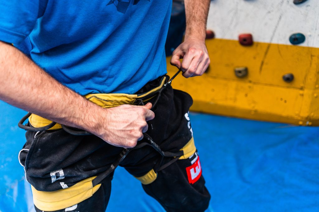 Man adjusts rock climbing body harness