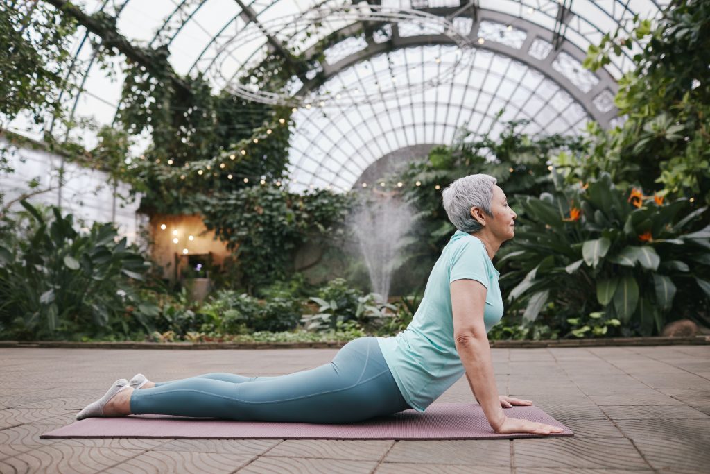 Woman lays across yoga mat doing a sphinx stretch